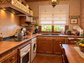 Eine Küche mit integriertem Backofen, Spüle und einem Fenster mit Blick auf Grünflächen.