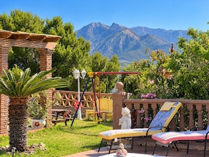 Eine Terrasse mit Gartenmöbeln, einer Schaukel und Blick auf Berge.