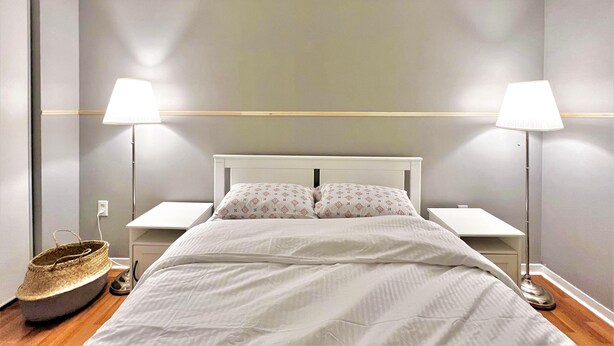 Un dormitorio con cama, dos lámparas de noche, una mesita de noche y una lámpara de pie.