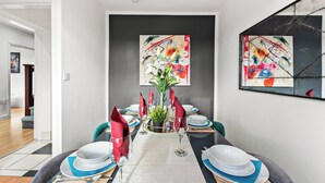 A dining area with a long table set for six, featuring a central vase with greenery and red napkins. - Stylish Langley Mill Stay | Sleeps 11 (Langley Mill)