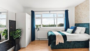 A bedroom with a bed, a window, curtains, a radiator, and a potted plant. - Stylish Langley Mill Stay | Sleeps 11 (Langley Mill)