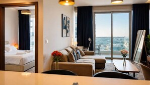 Habitación de hotel con cama, sofá, mesa de comedor y vista a la ciudad.