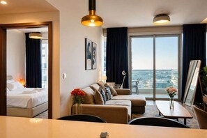 Habitació d'hotel amb llit, sofà, taula de dinar i vista a la ciutat.