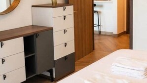 A hotel room with a bed, a dresser with drawers, a mirror, and a kitchenette area. - 1BR in a Landmark Tower  Rooftop Pool, 360° Views, Near Metro (Dubai)