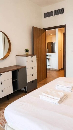 A hotel room with a bed, a dresser with drawers, a mirror, and a kitchenette area. - 1BR in a Landmark Tower  Rooftop Pool, 360° Views, Near Metro (Dubai)