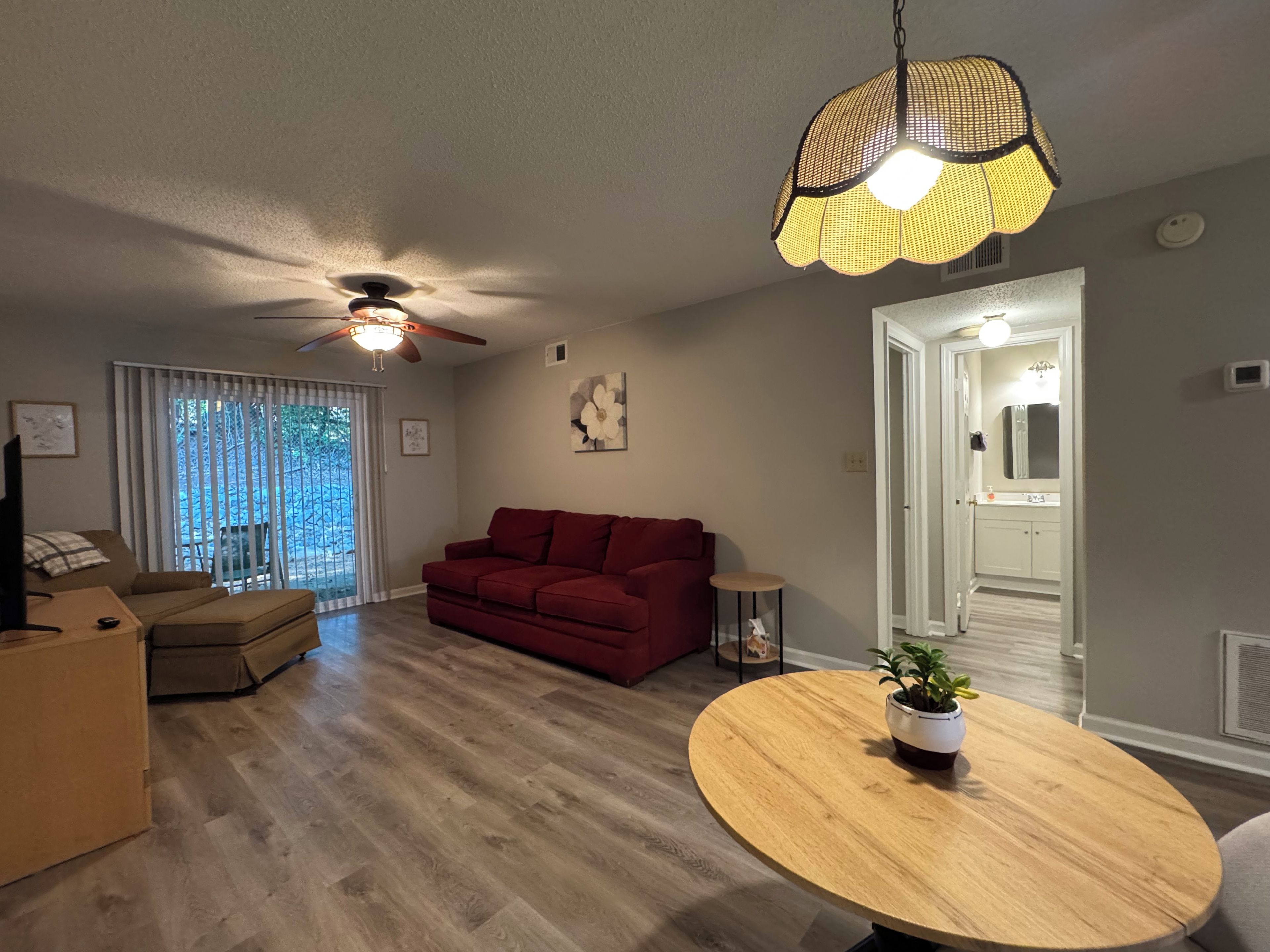 Un salon avec un canapé rouge, une table basse en bois et un ventilateur de plafond.