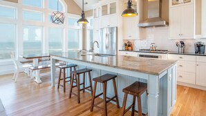 A kitchen with a large island, wooden stools, and a view of the ocean. - RARE Short-term rental on Exclusive Pine Island! Oceanfront&Pool, Oct 8-11, 2026 (Corolla)