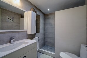 A modern bathroom with a white sink, a mirror, a cabinet, a shower area, and a toilet. - Apartment 'Right in The Golden Mile 200 Metres' with Shared Pool, Wi-Fi and Air Conditioning (Marbella)