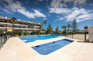 Ein Swimmingpool mit blauem Himmel und einem mehrstöckigen Gebäude im Hintergrund.