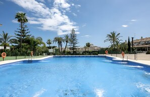A swimming pool with lifebuoys, surrounded by palm trees and a clear sky. - Apartment 'Right in The Golden Mile 200 Metres' with Shared Pool, Wi-Fi and Air Conditioning (Marbella)