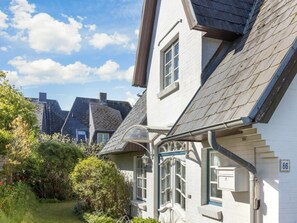 A residential building with a sloped roof, white exterior walls, and a visible number '86' on the side. - Holiday Apartment Sylt 86 (Sylt)