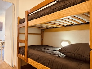 A bunk bed with a wooden frame and a window at the head. - Bright studio ski slopes view for (Les Deux Alpes)