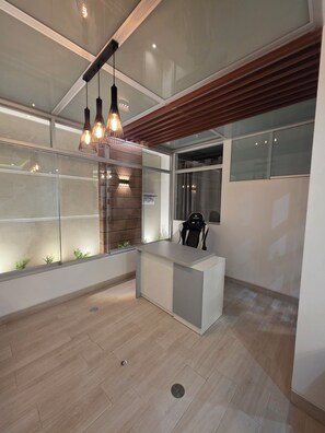A modern office space with a reception desk, pendant lighting, and a view through large windows. - Comfortable Apartment in Cusco | Families and Groups (Cusco)