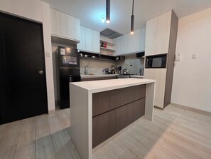 A modern kitchen with a central island, built-in appliances, and pendant lighting. - Comfortable Apartment in Cusco | Families and Groups (Cusco)