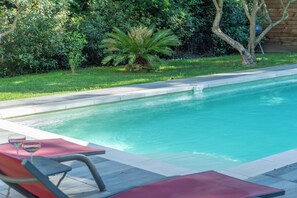 A swimming pool with a clear blue water surface, surrounded by a grassy area and various plants. - House consisting of 3 independent apartments with air conditioning, a terrace, parking, and a garden (Aubais)