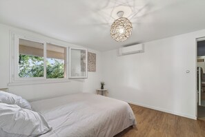 A bedroom with a bed, a window, and a ceiling light fixture. - House consisting of 3 independent apartments with air conditioning, a terrace, parking, and a garden (Aubais)