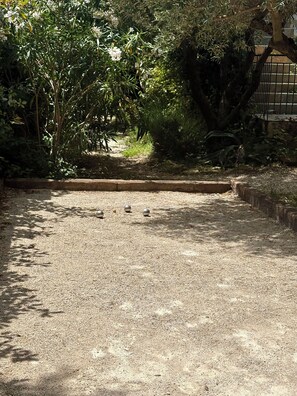 A gravel path leading through a garden with dense foliage and a metal fence. - House consisting of 3 independent apartments with air conditioning, a terrace, parking, and a garden (Aubais)