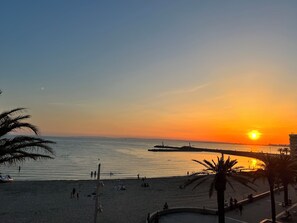 A beach with a sunset, palm trees, and a pier. - House consisting of 3 independent apartments with air conditioning, a terrace, parking, and a garden (Aubais)
