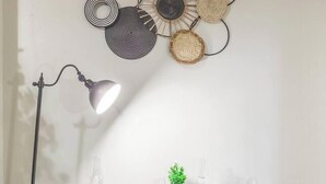 A dining area with a table set for two, a floor lamp, and a wall-mounted decorative piece. - Modern Studio in Allentown (Buffalo)