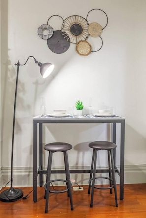 Un comedor con una mesa preparada para dos, una lámpara de pie y un adorno en la pared.