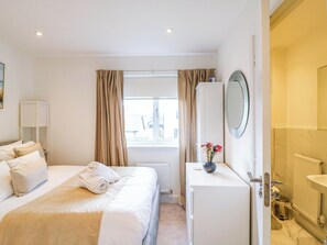 Ein Hotelzimmer mit Bett, Schreibtisch, Spiegel und einem Fenster mit Vorhängen.