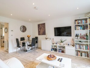 Ein modernes Wohnzimmer mit Essbereich, Bücherregal und Fernseher.