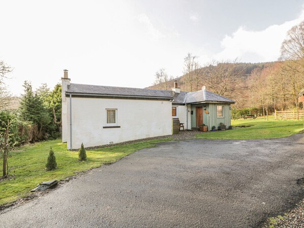 A two-story house with a gravel driveway and a small garden area. - The Sheiling (Callander)