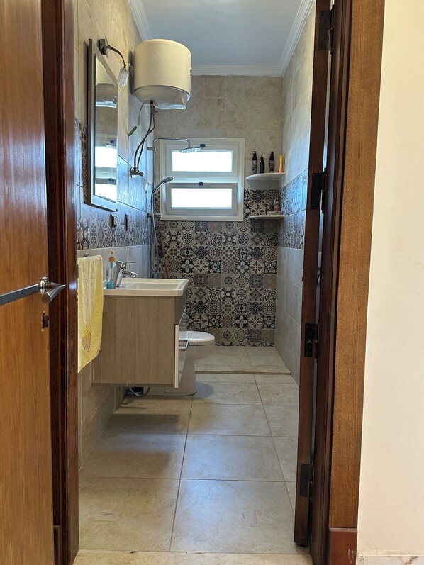 A bathroom with a toilet, sink, and shower area.