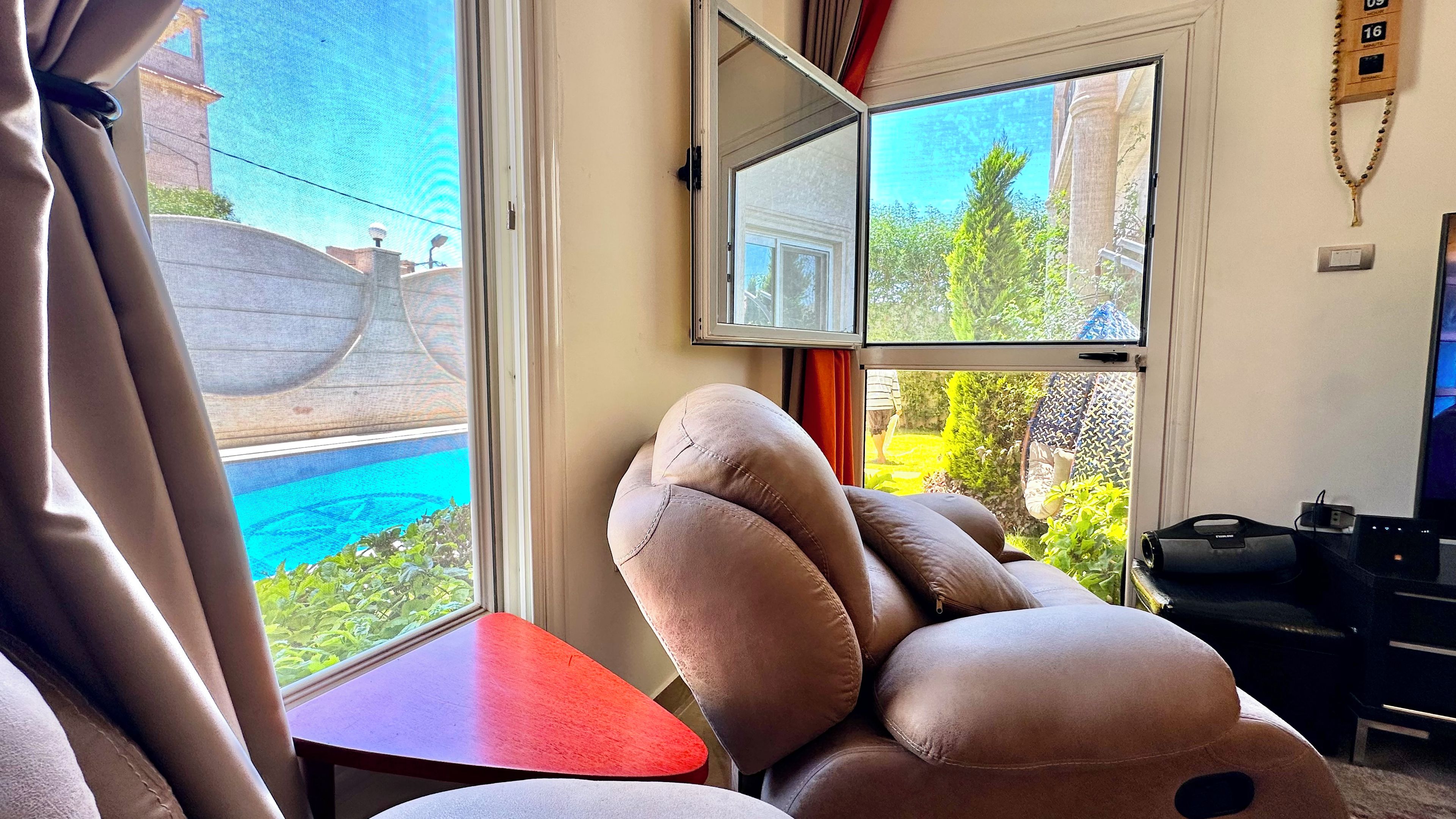 A room with a large window, a red table, and a large plush toy.