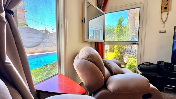 A room with a large window, a red table, and a large plush toy.