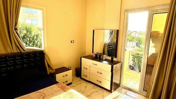 A hotel room with a bed, a dresser, a mirror, and a sliding glass door leading to a balcony.