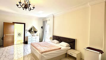 A bedroom with a bed, bedside tables, a mirror, a chandelier, and a wardrobe.