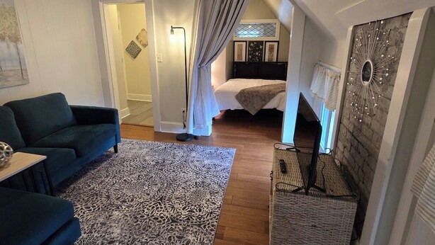 A room with a bed, a blue sofa, a patterned rug, and a wall-mounted TV. - Homey Private Penthouse (Buffalo)