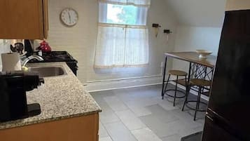 A kitchen with a stove, sink, and a dining area with a table and chairs.