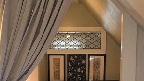 A bedroom with a bed, a window with a metal grid, a wall-mounted artwork, and a wooden floor. - Homey Private Penthouse (Buffalo)