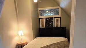 A bedroom with a bed, a nightstand, a lamp, and a ceiling light. - Homey Private Penthouse (Buffalo)