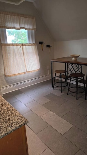 A kitchen with a window, a table, two chairs, and a countertop.