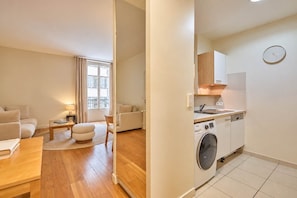 Un apartament modern amb zona de saló, menjador i cuina equipada amb rentadora.