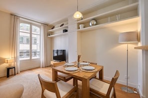 En moderne stue med et spisebord dækket til fire personer, et fjernsyn og en gulvlampe.