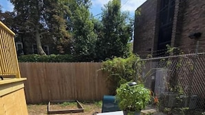 A backyard with a picnic table and chairs, a potted plant, and a wooden fence. - Patio Perfection in Allentown (Buffalo)