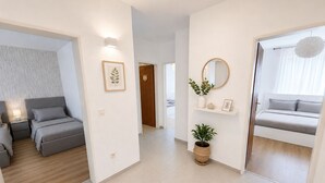Moderni hotellihuone, jossa on sänky, yöpöytä ja näkymä käytävälle.