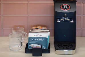 Een koffieapparaat, een koffiepadapparaat en twee glazen op een aanrecht.