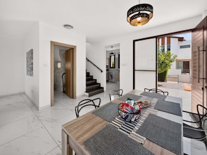 A modern interior with a dining area, staircase, and a view of the outside. - Villa Buena Vida, Ayia Triada Pool Home (Pernera)
