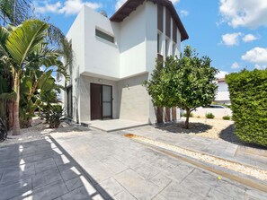 A modern two-story building with a flat roof, large windows, and a paved driveway. - Villa Buena Vida, Ayia Triada Pool Home (Pernera)