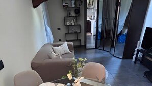 Een moderne eethoek met een glazen tafel, twee stoelen en een vaas met bloemen.