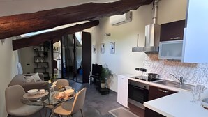 Een moderne keuken met een eethoek, voorzien van een glazen tafel, stoelen en een inbouwoven.