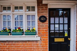 A black door with a brass knocker, a window with lace curtains, and a number plate '42A' on the wall. - The Royal Exchange House in Canterbury (Kent)