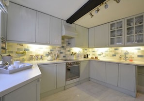 A kitchen with white cabinets, a stove, and a tiled backsplash. - The Royal Exchange House in Canterbury (Kent)