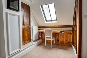 A room with a sloped ceiling, a skylight, a radiator, a white chair, and wooden cabinets. - The Royal Exchange House in Canterbury (Kent)