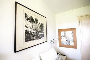 Ein Zimmer mit einem Bett, einem gerahmten Schwarz-Weiß-Foto an der Wand, einer Nachttischlampe und einem Spiegel.